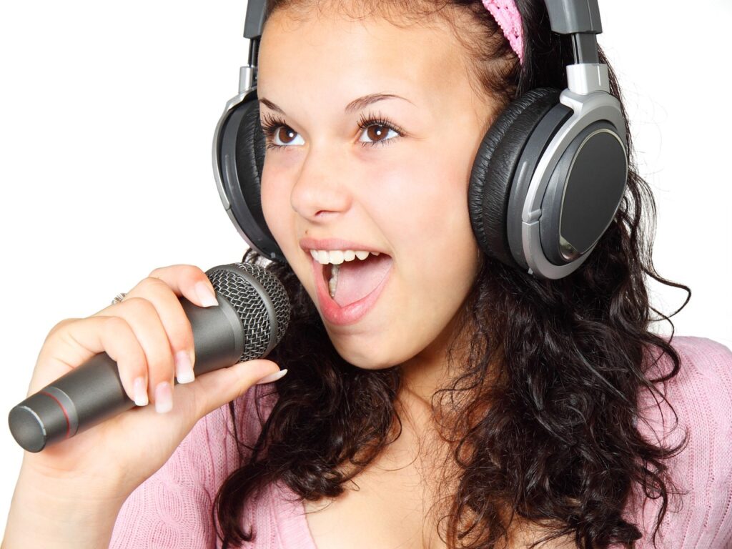 Singendes Mädchen mit Kopfhörern und Mikrofon